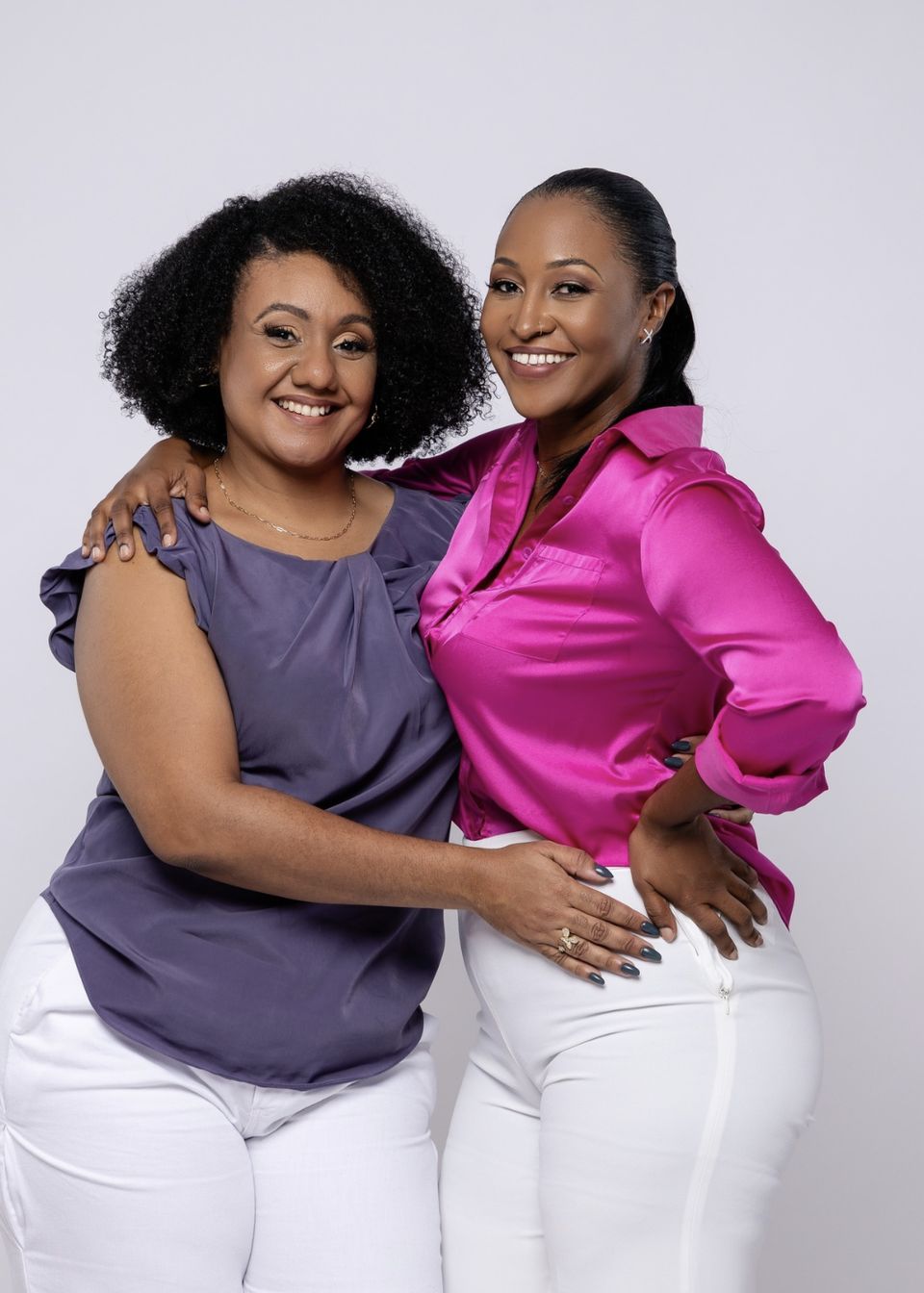 Janique and Tasana, the two founders of Just Creative, standing side by side and smiling in a warm editorial portrait taken in St. Maarten